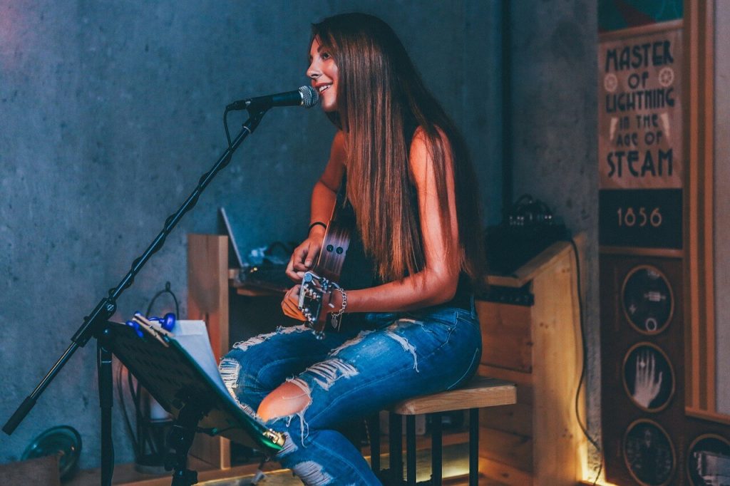 A beautiful girl with long hair plays the guitar and sings