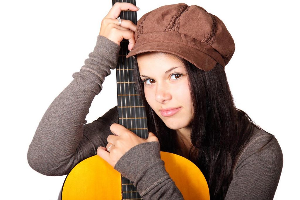 A girl with a hat holds a classical guitar