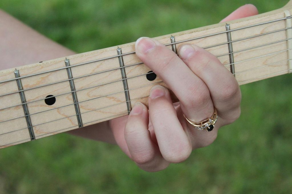 A woman's hand with a ring playing a guitar